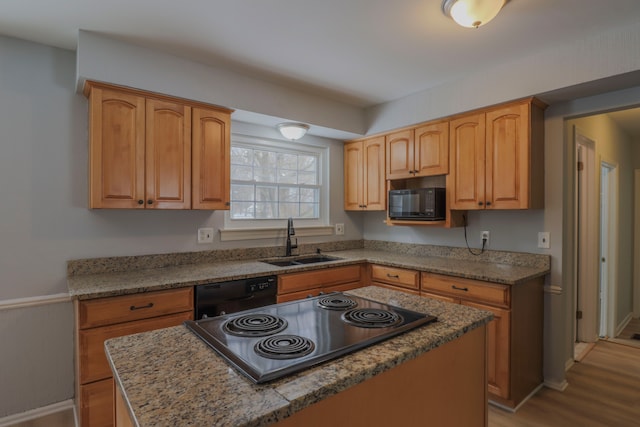 kitchen featuring a kitchen island, sink, light wood-type flooring, and black appliances