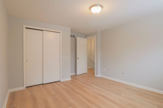 unfurnished bedroom with light wood-type flooring and a closet