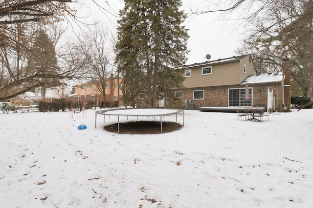 snow covered back of property featuring central AC unit