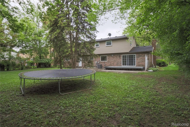 6868 Vachon Dr, Bloomfield Hills, MI 48301 - back of house featuring a trampoline, a yard, a chimney, cooling unit, and brick siding