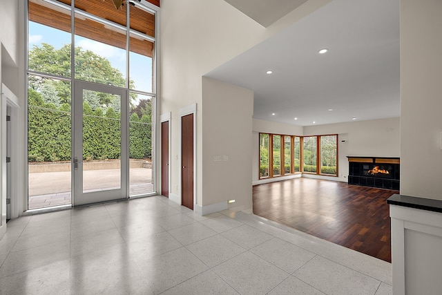 interior space featuring a tiled fireplace, plenty of natural light, and a towering ceiling