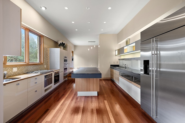 kitchen featuring a kitchen island, appliances with stainless steel finishes, dark hardwood / wood-style floors, white cabinetry, and hanging light fixtures