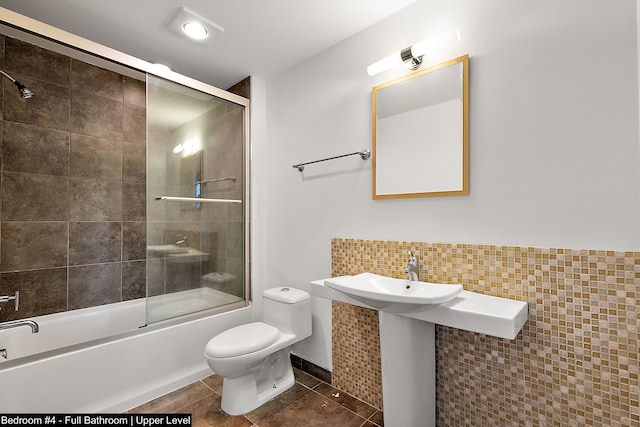 full bathroom featuring combined bath / shower with glass door, sink, tile patterned floors, and toilet