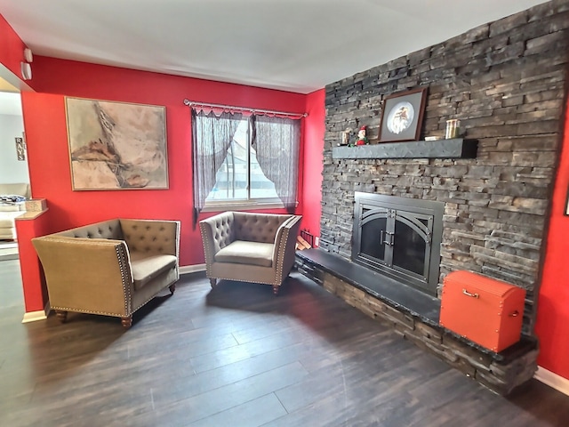 sitting room with dark hardwood / wood-style floors and a stone fireplace