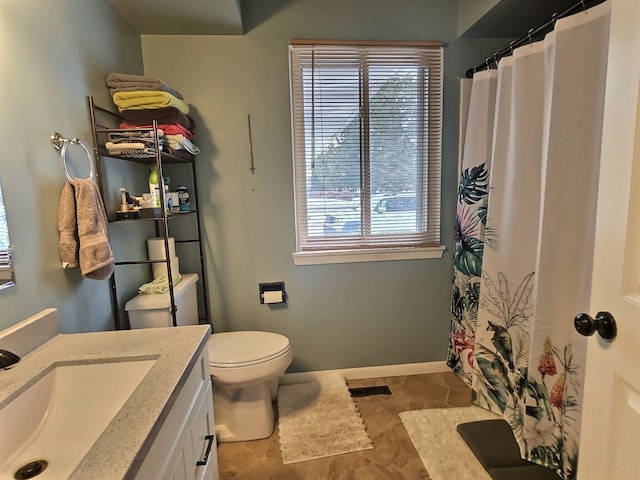 bathroom featuring vanity, a healthy amount of sunlight, tile patterned floors, and toilet