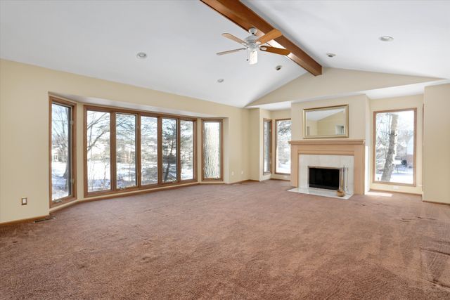 unfurnished living room with plenty of natural light, carpet, and vaulted ceiling with beams