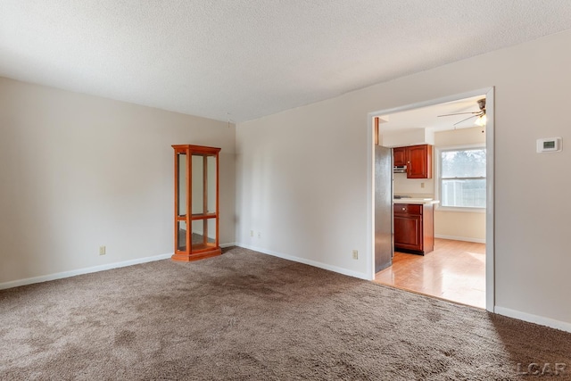 carpeted spare room featuring ceiling fan and a textured ceiling