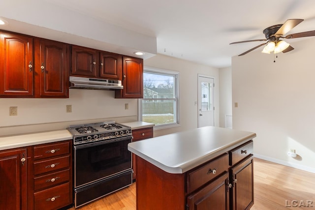 kitchen with ceiling fan, a kitchen island, black gas range oven, and light hardwood / wood-style floors