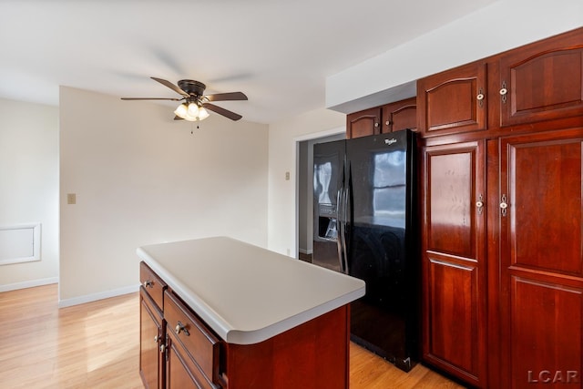 kitchen featuring black fridge with ice dispenser, light hardwood / wood-style flooring, ceiling fan, and a kitchen island