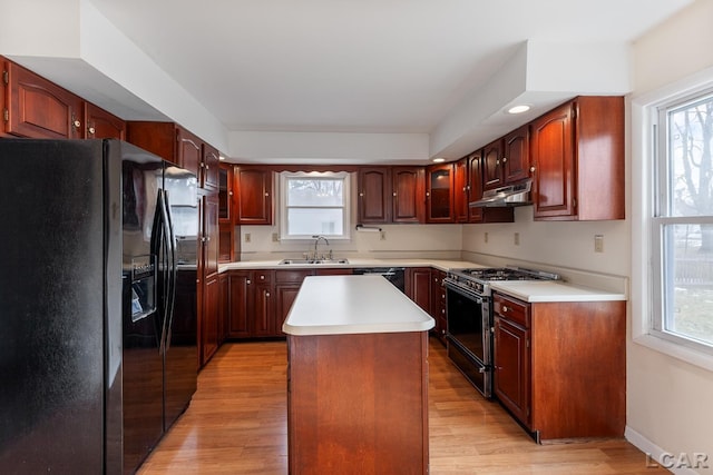 kitchen featuring a center island, sink, light wood-type flooring, and black appliances