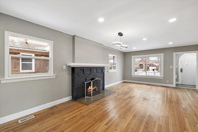 unfurnished living room featuring a brick fireplace and light hardwood / wood-style flooring