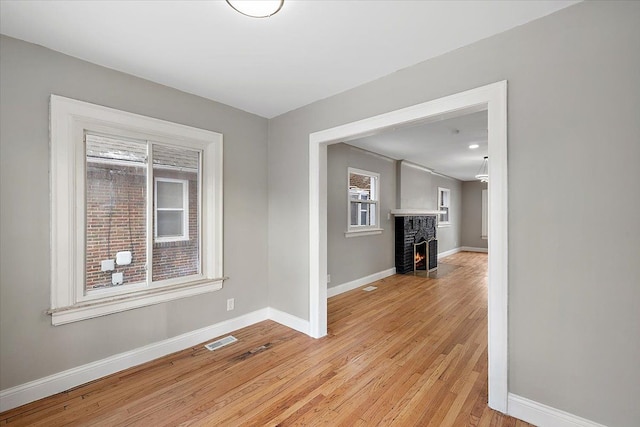 empty room with a fireplace and light wood-type flooring