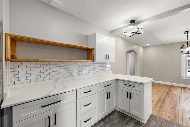 kitchen with pendant lighting, white cabinetry, light stone counters, tasteful backsplash, and kitchen peninsula