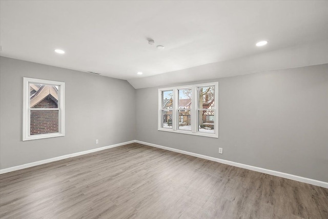 spare room featuring lofted ceiling and hardwood / wood-style floors