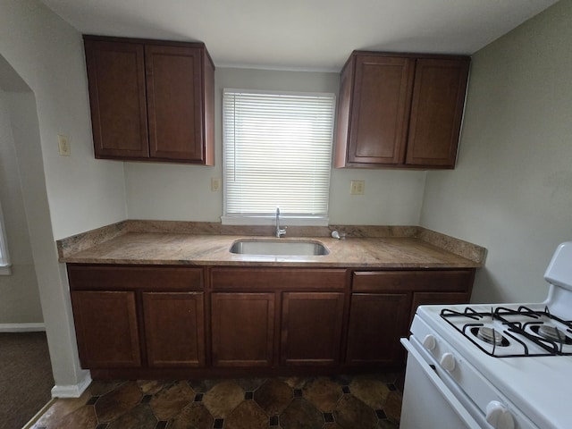 kitchen featuring dark brown cabinets, sink, and white gas range oven