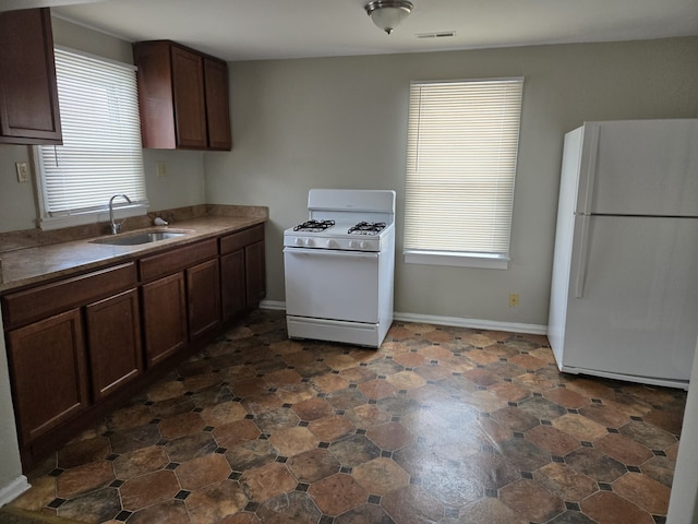 kitchen with dark brown cabinetry, sink, and white appliances