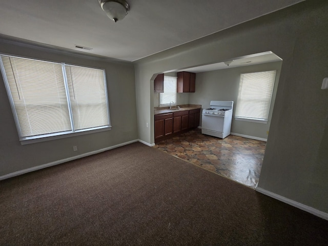 kitchen featuring sink, white gas range oven, and dark colored carpet