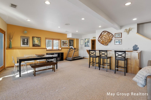 dining space featuring light colored carpet, bar, and beam ceiling