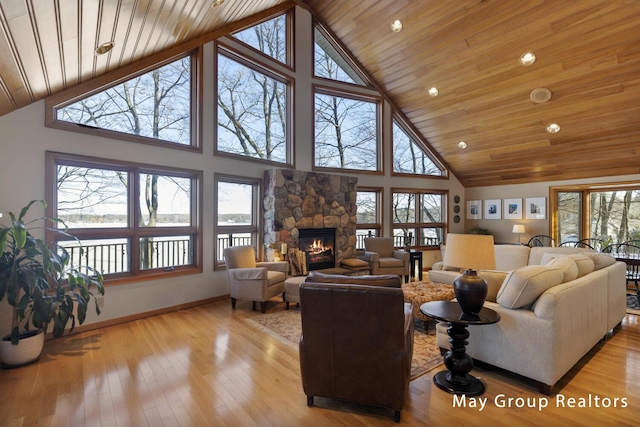 living room featuring a stone fireplace, a towering ceiling, wood ceiling, and light wood-type flooring