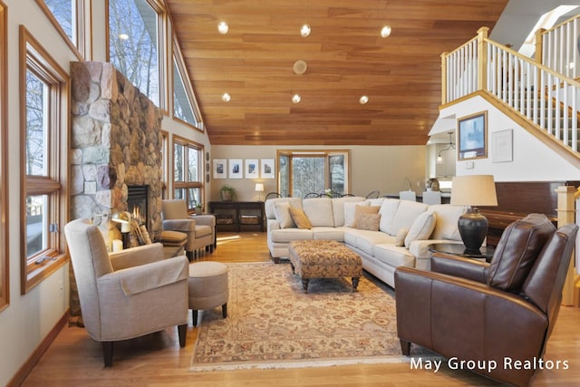 living room featuring wood ceiling, light hardwood / wood-style flooring, and a stone fireplace