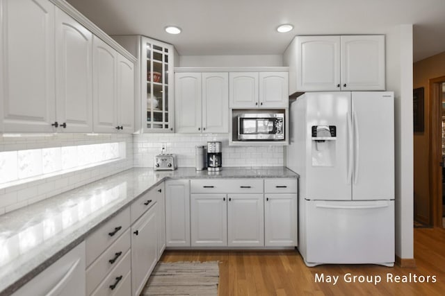 kitchen featuring white cabinetry, stainless steel microwave, and white fridge with ice dispenser