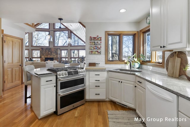 kitchen featuring white cabinetry, hanging light fixtures, white dishwasher, kitchen peninsula, and range with two ovens