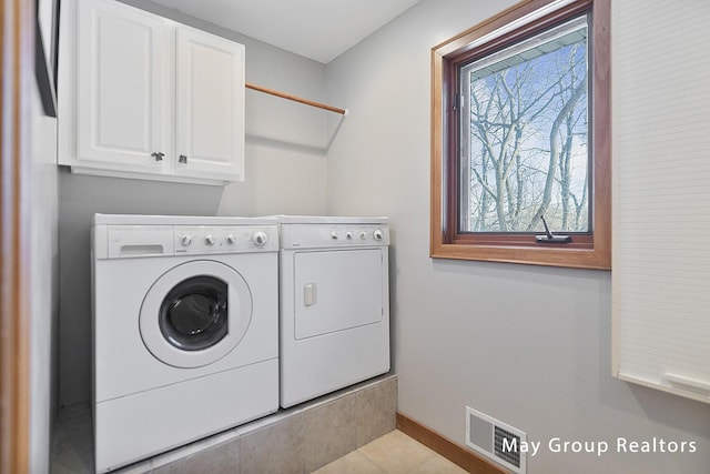 clothes washing area featuring light tile patterned flooring, cabinets, and separate washer and dryer