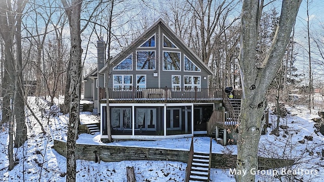 snow covered property with a sunroom and a deck