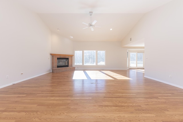 unfurnished living room featuring ceiling fan, high vaulted ceiling, a fireplace, and light hardwood / wood-style flooring