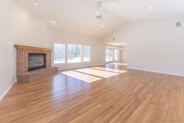 unfurnished living room featuring a brick fireplace, light hardwood / wood-style flooring, high vaulted ceiling, and ceiling fan