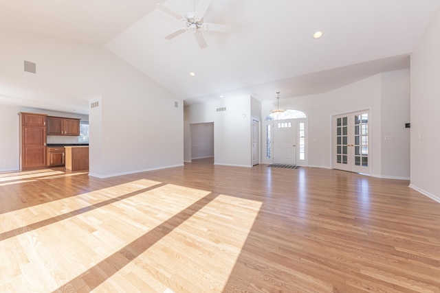 unfurnished living room with ceiling fan, high vaulted ceiling, and light wood-type flooring