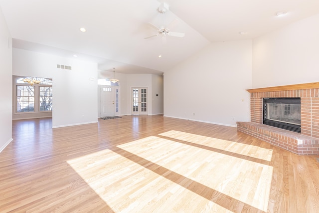 unfurnished living room with ceiling fan, lofted ceiling, light wood-type flooring, and a fireplace