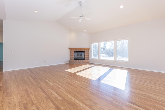 unfurnished living room with ceiling fan, lofted ceiling, a fireplace, and light hardwood / wood-style floors