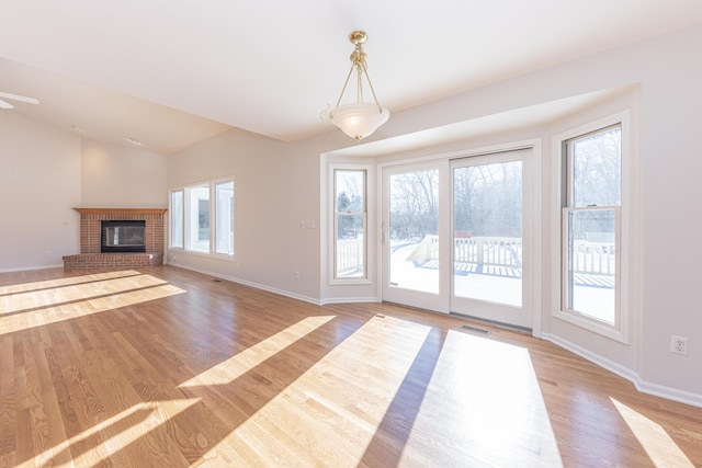 unfurnished living room featuring lofted ceiling, a fireplace, and light hardwood / wood-style floors