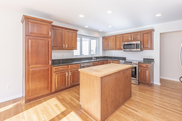 kitchen with butcher block counters, sink, light wood-type flooring, appliances with stainless steel finishes, and a kitchen island