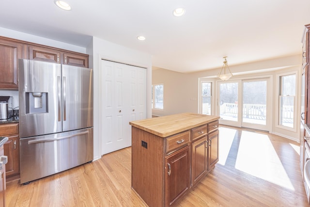 kitchen featuring butcher block counters, a center island, hanging light fixtures, light wood-type flooring, and stainless steel fridge