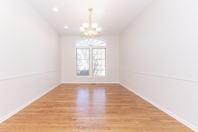 spare room with a chandelier and light hardwood / wood-style flooring