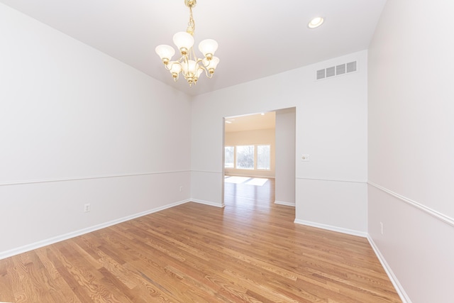 unfurnished room with a chandelier and light hardwood / wood-style floors