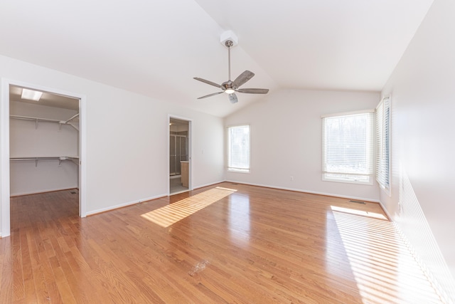 unfurnished room with ceiling fan, a wealth of natural light, vaulted ceiling, and light wood-type flooring