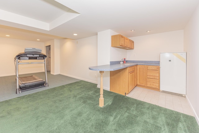 kitchen with light brown cabinetry, a kitchen breakfast bar, white refrigerator, light carpet, and kitchen peninsula