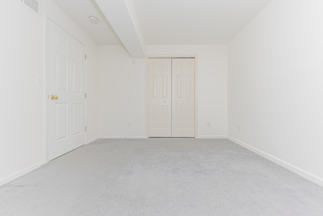 unfurnished bedroom featuring light carpet and a closet