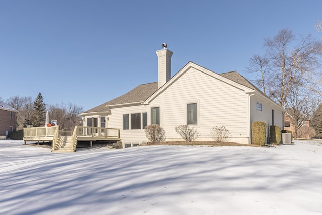 snow covered back of property featuring a wooden deck and central AC