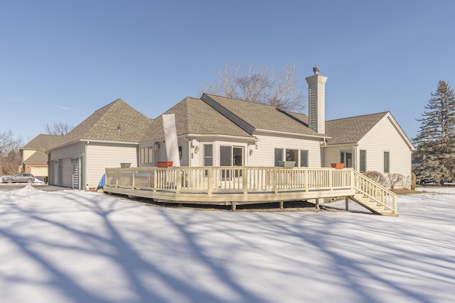 snow covered house with a wooden deck and a garage