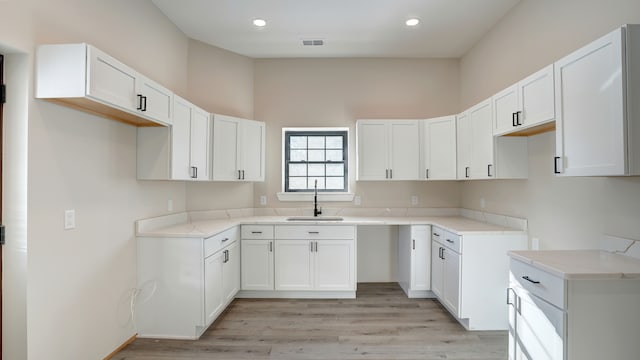 kitchen featuring sink, light hardwood / wood-style flooring, and white cabinets