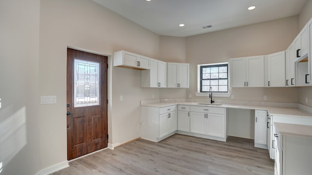 kitchen with white cabinetry, sink, and light hardwood / wood-style floors