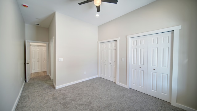 unfurnished bedroom featuring multiple closets, light carpet, and ceiling fan