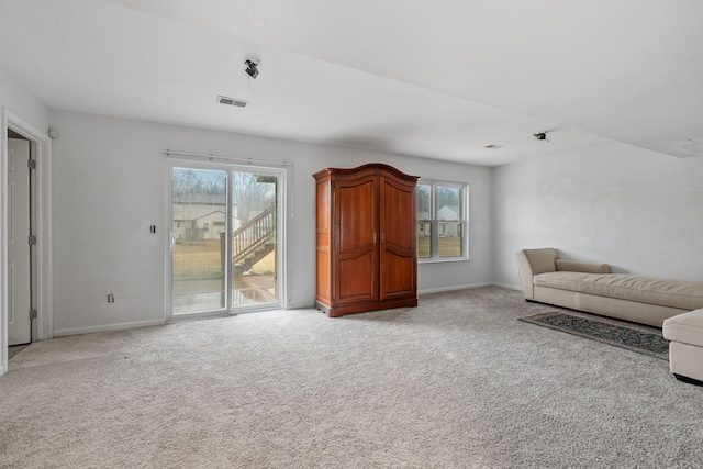 unfurnished living room featuring light carpet and a healthy amount of sunlight