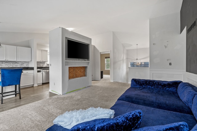 carpeted living room featuring vaulted ceiling and a notable chandelier