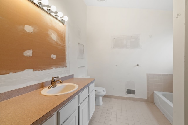 bathroom featuring tile patterned flooring, toilet, vanity, and a tub to relax in