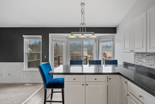 kitchen featuring white cabinetry, a kitchen bar, and pendant lighting